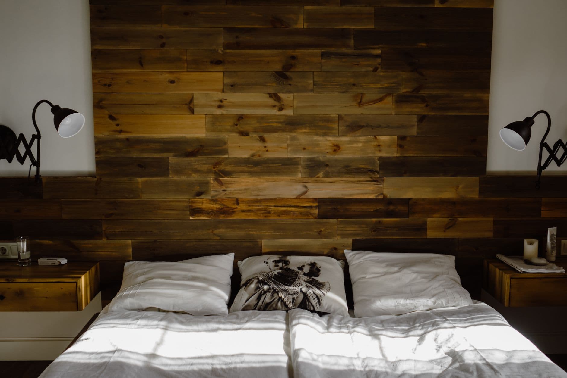 A small lamp clamped to the edge of a bed headboard beside an open book