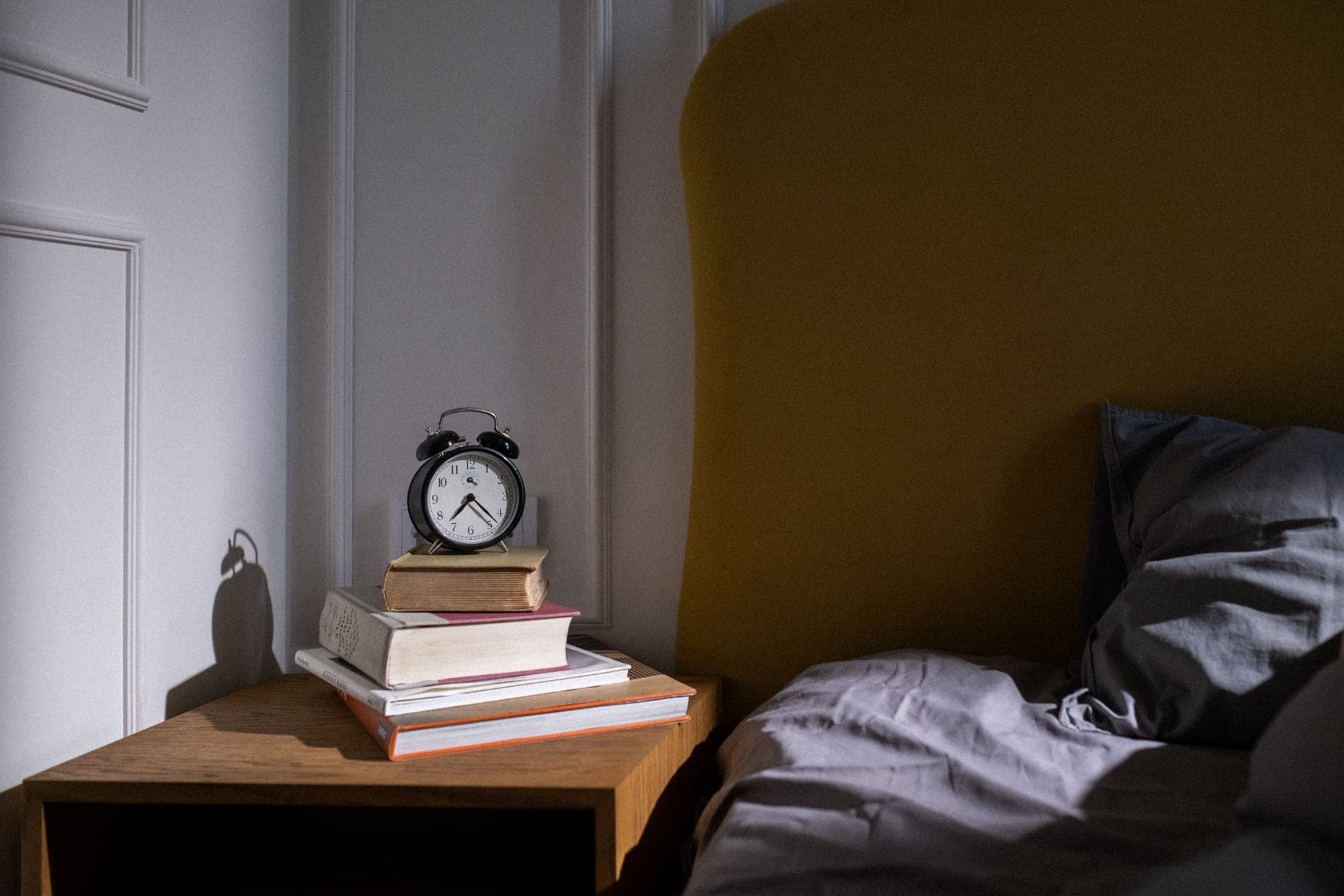 A stack of books resting on a bed in morning light