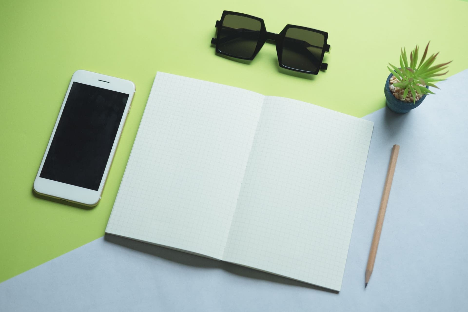 A phone and an open notebook side by side on a desk