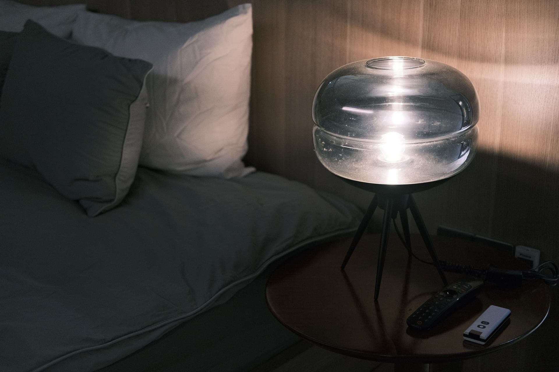A small reading lamp glowing on a bedside table at night