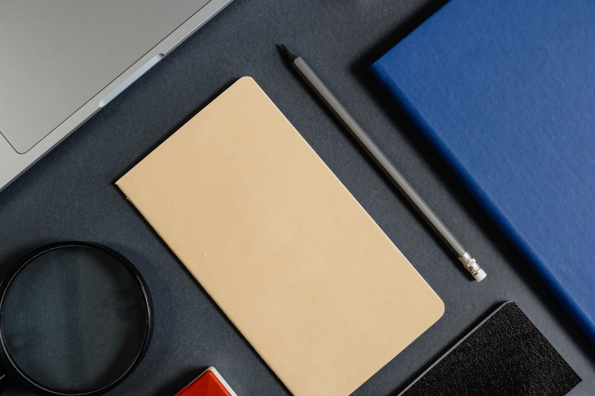 A book and a magnifying glass on a dark wooden desk