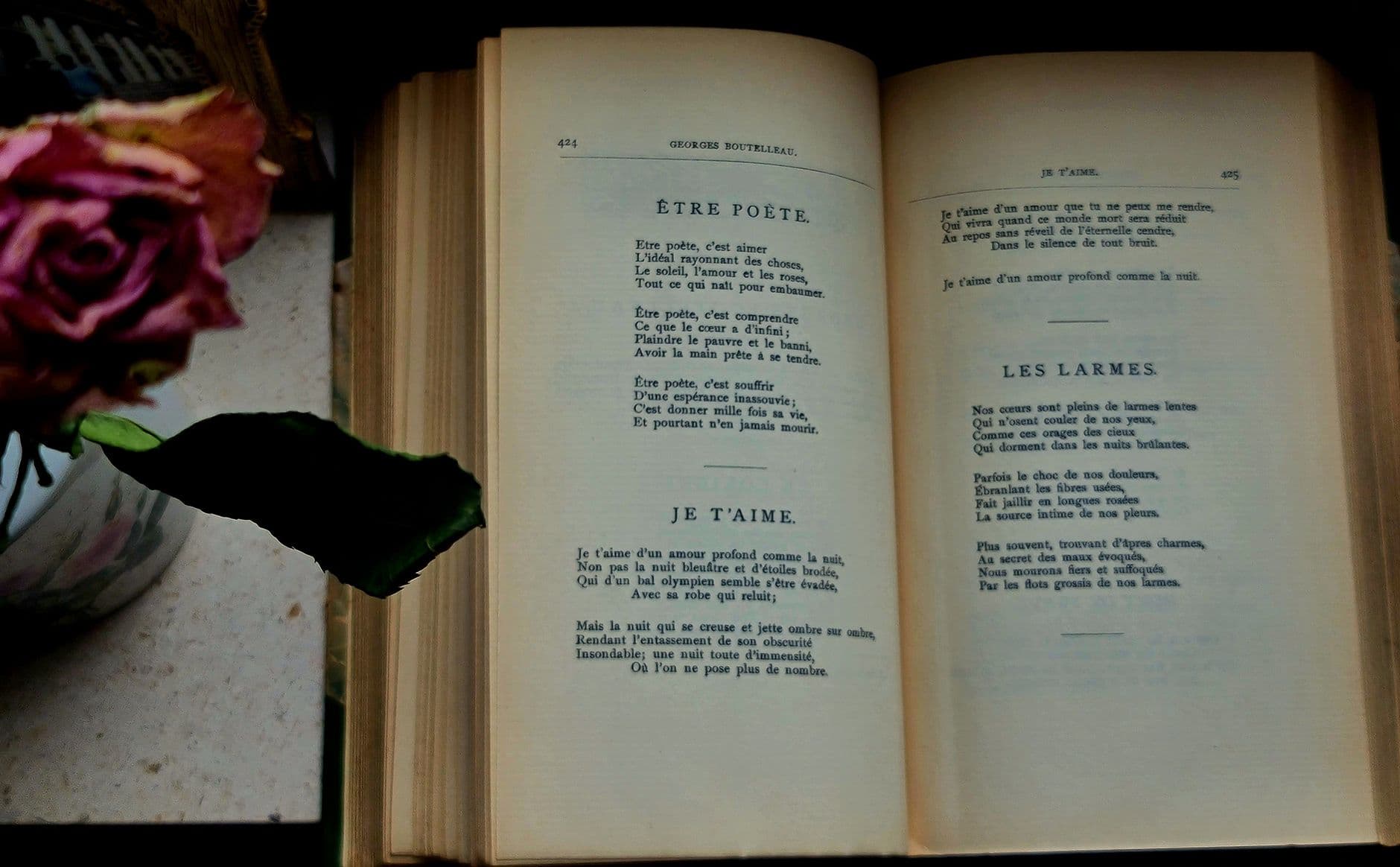 An open book of poetry on a table beside a cup
