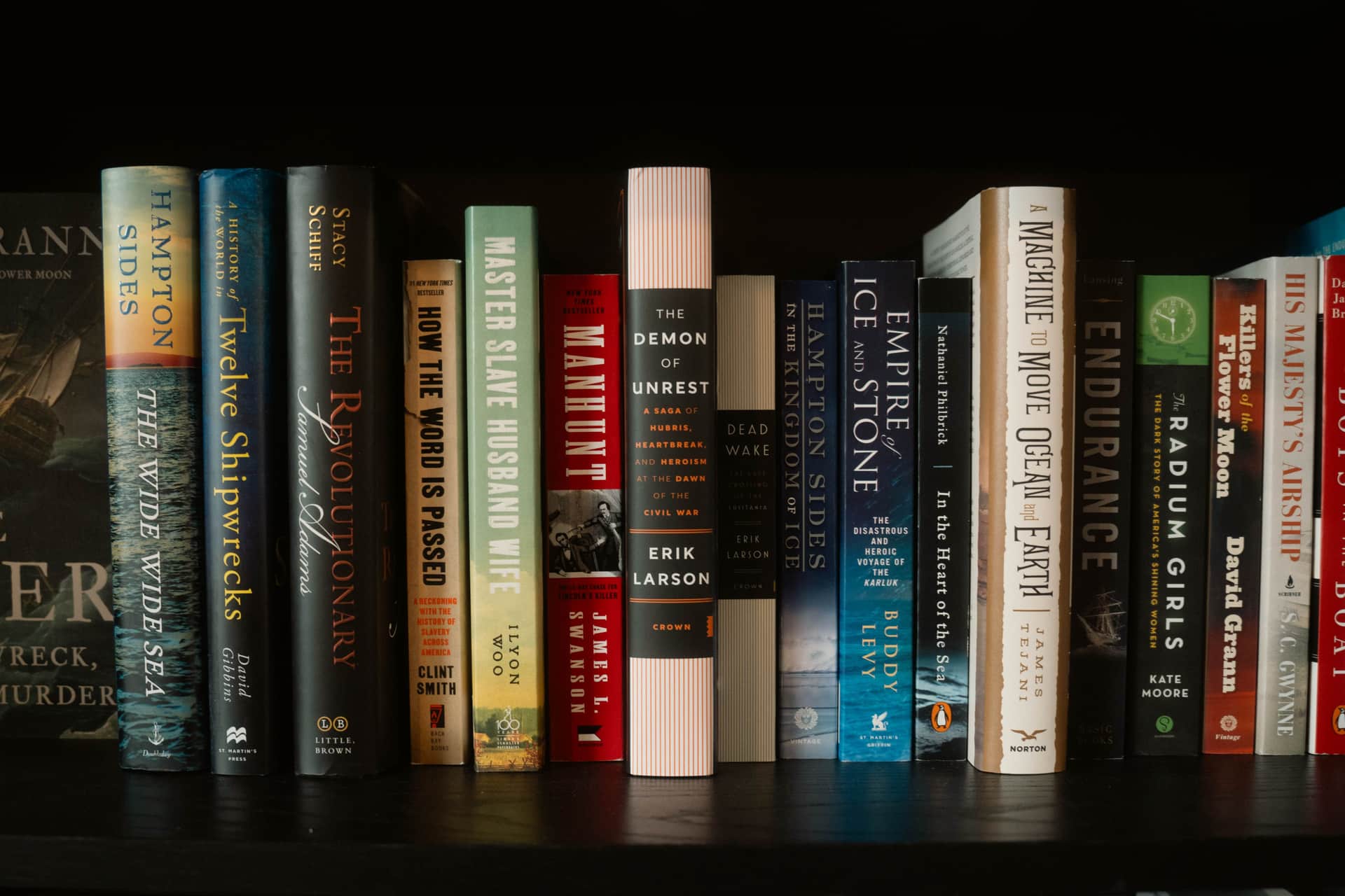 A shelf of paperback books packed tightly together, spines facing out